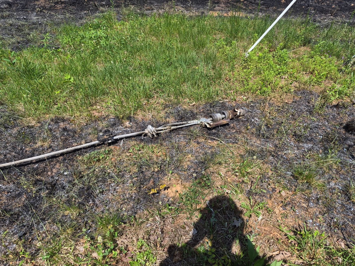 A downed power conductor in scorched grass at the Energix solar farm